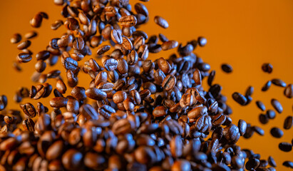 Explosion of freshly roasted brown coffee beans on yellow studio background. Fragrant coffee seeds...
