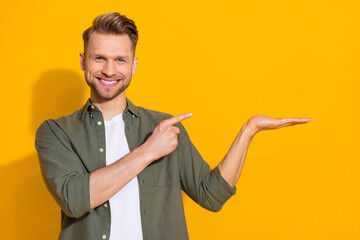 Portrait of attractive cheerful confident blond guy demonstrating copy space isolated over bright yellow color background