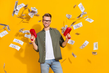 Portrait of attractive cheerful rich guy shooting us dollars loan exchange isolated over bright yellow color background
