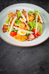 salad with fried chicken and bacon on a black background