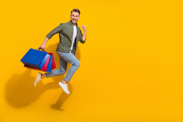 Fototapeta na wymiar Full length body size view of attractive lucky guy jumping carrying things running copy space isolated over bright yellow color background