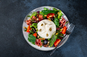 Burrata, Italian fresh cheese made from cream and milk of buffalo or cow. Burrata salad with tomatoes and salad mix. Healthy eating concept. Keto diet salad.
