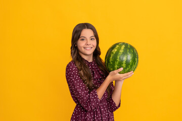 happy kid holding fresh ripe water melon fruit on yellow background, summer