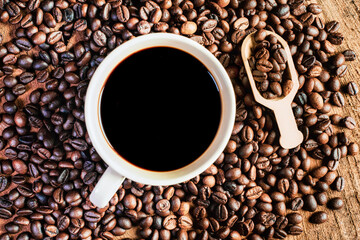 Black coffee in the cup, Dark Coffee beans on the old wooden floor,  Close up of seeds of coffee.