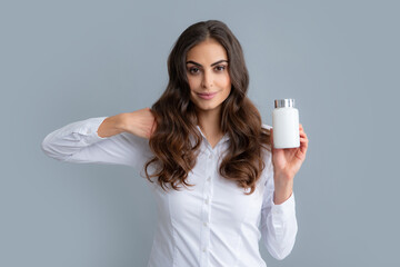 Healthy hair care concept. Woman with bottle pills. Young woman holding a vitamins isolated grey...