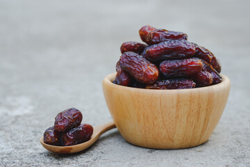 Dates in wooden cups and wooden spoons on cement floor. Muslims like to eat during fasting. (Ramadan) because it can help the body that is exhausted from fasting.