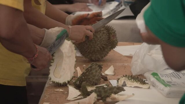 Peeling durian fruit with a knife, close up, slow motion.