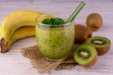 Vitamin smoothie from kiwi and banana on a white wooden background.
