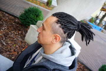 men's dreadlocks hairstyle gathered in a ponytail, profile portrait