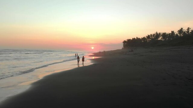 Romantic couple walk together at sunset in tropical sand beach, bali island aerial view