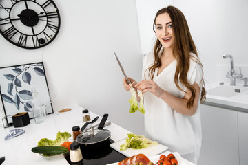 Young, Beautiful Girl is Preparing Breakfast in a Modern, White Kitchen. Omelet and Seasoned Vegetables on Countertop