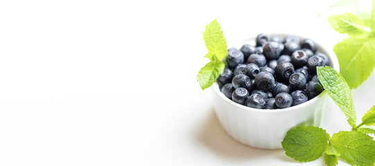 Advertising banner. White bowl with forest blueberries on white close up. Copy space.