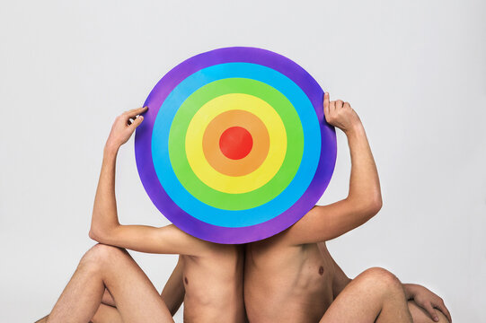 two naked men hold rainbow target and hide their faces, concept of LGBTQ pride, LGBTQ people, LGBTQ rights campaign, same sex marriage