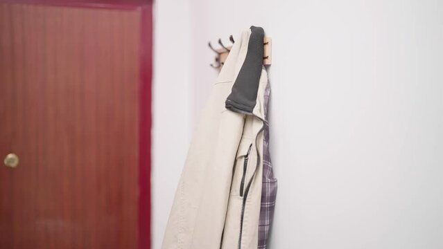 Person hand hang stylish beige jacket on hook 4K