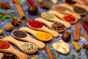A set of spices on a gray background. Variety of spices from India. Food decoration design. Various spices, peppers and herbs close-up top view. Set of peppers, salt, herbs and spices for cooking.