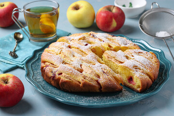 Homemade apple pie sprinkled with powdered sugar, on light blue background