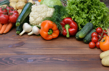 A set vegetables on a wooden background: carrots, potatoes, zucchini, paprika, cucumber, garlic, tomatoes, lettuce.Healthy food concept with vegetables and ingredients for cooking. Top view.Copy space