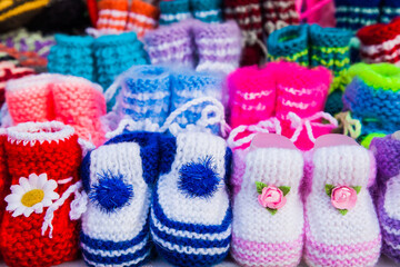 Fototapeta na wymiar Knitted baby booties in other knitted things on the background.