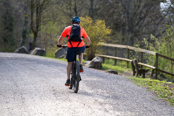 Mountain biker on gravel road way up at local mountain Uetliberg on a sunny spring day. Photo taken April 14th, 2022, Zurich, Switzerland.