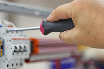 Mounting screwdriver in the hand of an electrical engineer close-up.
