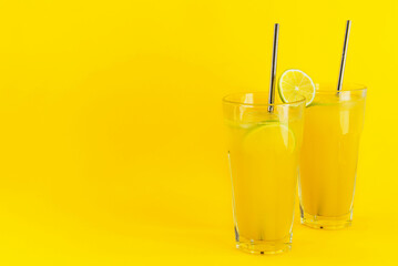 Homemade orange lemonade in glasses on a yellow background. Selective focus, copy space.