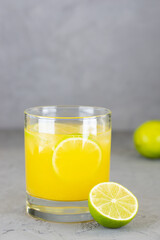 Citrus cocktail with lime in a glass on a gray background.