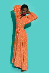 Black young woman in orange polka dot maxi dress.