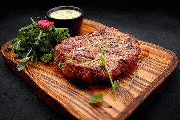 Pork neck steak with sauce and arugula, on a wooden board