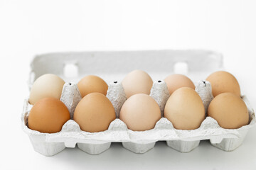Chicken eggs in carton box on wooden table.