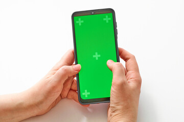 Elderly woman hands holding smartphone with green screen. Mock up mobile. The chromakey. Green screen
