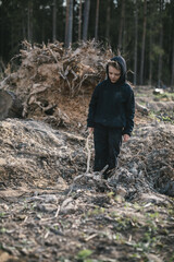 A boy walks among cut down trees. Russia.