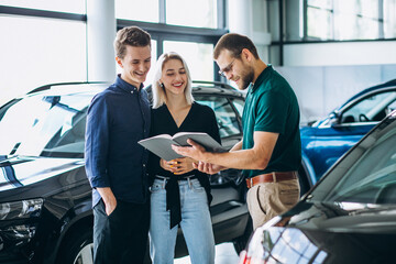 Couple choosing  a car in a car showroom and talking to the dealer