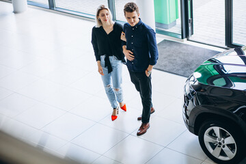 Young couple choosing a car in a car show room