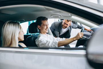 Young family buying a car in a car showroom