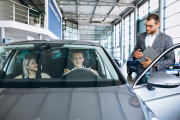 Young family buying a car in a car showroom