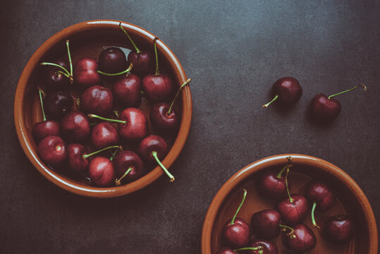 Overhead view of two bowls of cherries