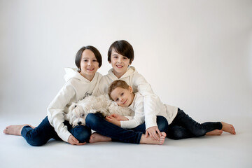 Cute stylish toddler child and older brothers, boys with white shirts on white background, family kids portrait