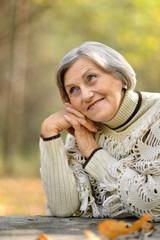 Portrait of nice smiling old woman posing in forest