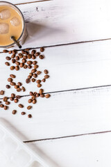 coffee ice cubes and beans with latte on white desk background top view