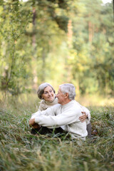 Portrait of beautiful senior couple sitting in autumn park