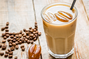 coffee break with cold iced latte and beans on wooden table background