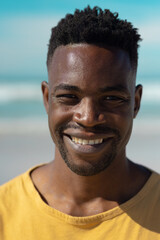 Close-up portrait of smiling handsome african american young man at beach against sky on sunny day