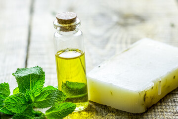 cosmetic oil in bottle and soap with herbs on light table background