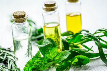 cosmetic oil in bottle with herbs on light table background