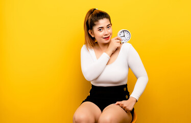 girl and alarm clock smiling holding an alarm clock isolated portrait from a yellow background