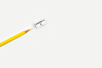 Lápiz amaillo de madera junto a un sacapuntas de metal sobre un fondo blanco liso y aislado. Vista superior y de cerca. Copy space