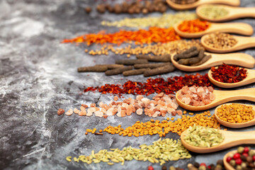 A set of spices on a gray background. Variety of spices from India. Food decoration design. Various spices, peppers and herbs close-up top view. Set of peppers, salt, herbs and spices for cooking.