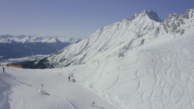 Austrian Alps drone reveal into Nordkette ski resort above Innsbruck, Skyline terrain park skier going off jump at ski resort
