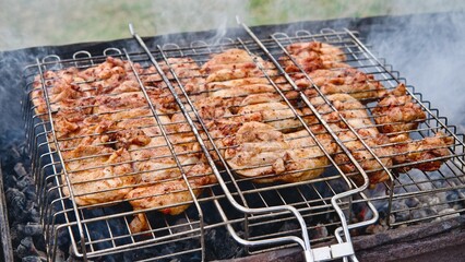 Cooking chicken meat outdoors at picnic time with barbecue grid. Grilled chicken meat BBQ. Close-up, selectine focus.