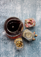 Still life with tea pot and glass jars of spices. Black tea, clove, cardamom. cinnamon, anise stars and lavender top view photo. Traditional spiced tea. 
